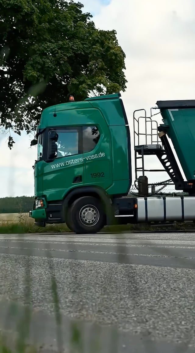 Grüne Zugmaschine mit Auflieger an einer Landstraße